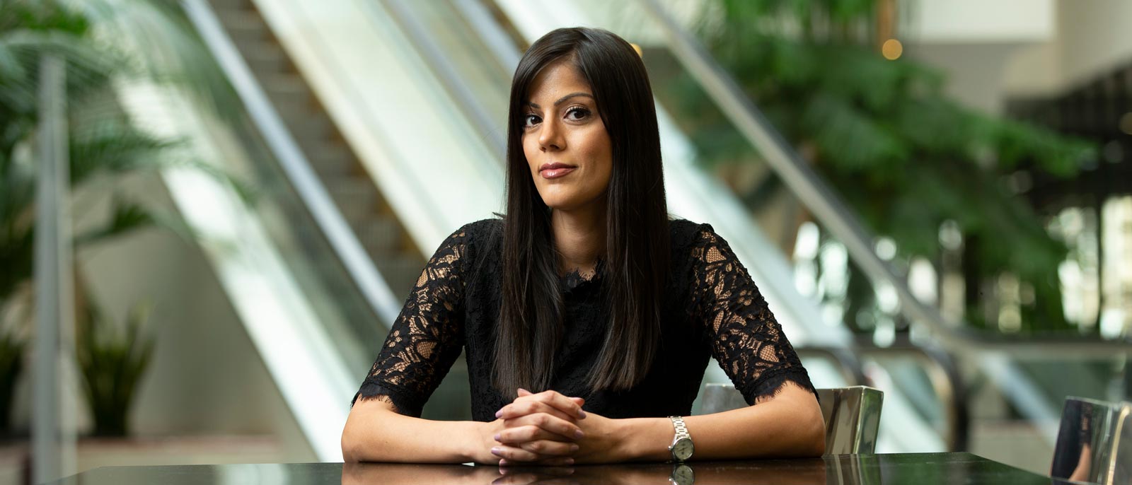 MSU Full-Time MBA alumnae Harprit Brar sits at a reflective metal table in an open atrium in East Lansing, Michigan.