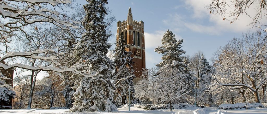 Beaumont Tower surrounded by trees in the winter with snow on the ground.