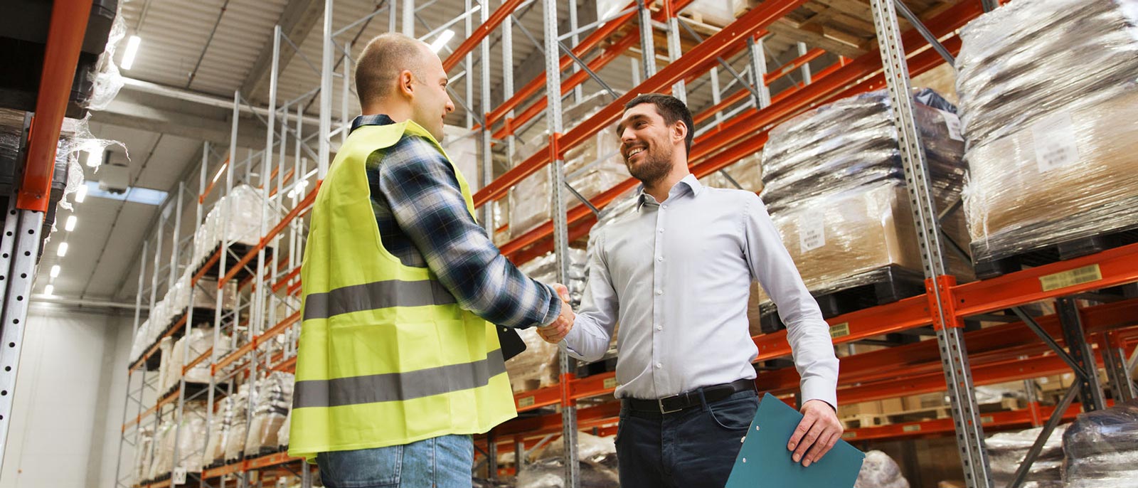 Two men in a warehouse shake hands.