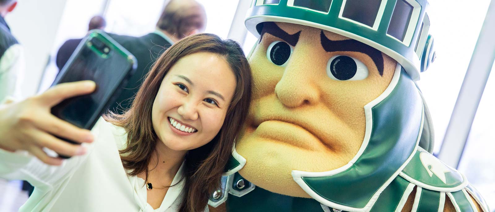 An undergraduate student and Sparty the mascot take a selfie at the 2018 Detroit Executive Forum in downtown Detroit.