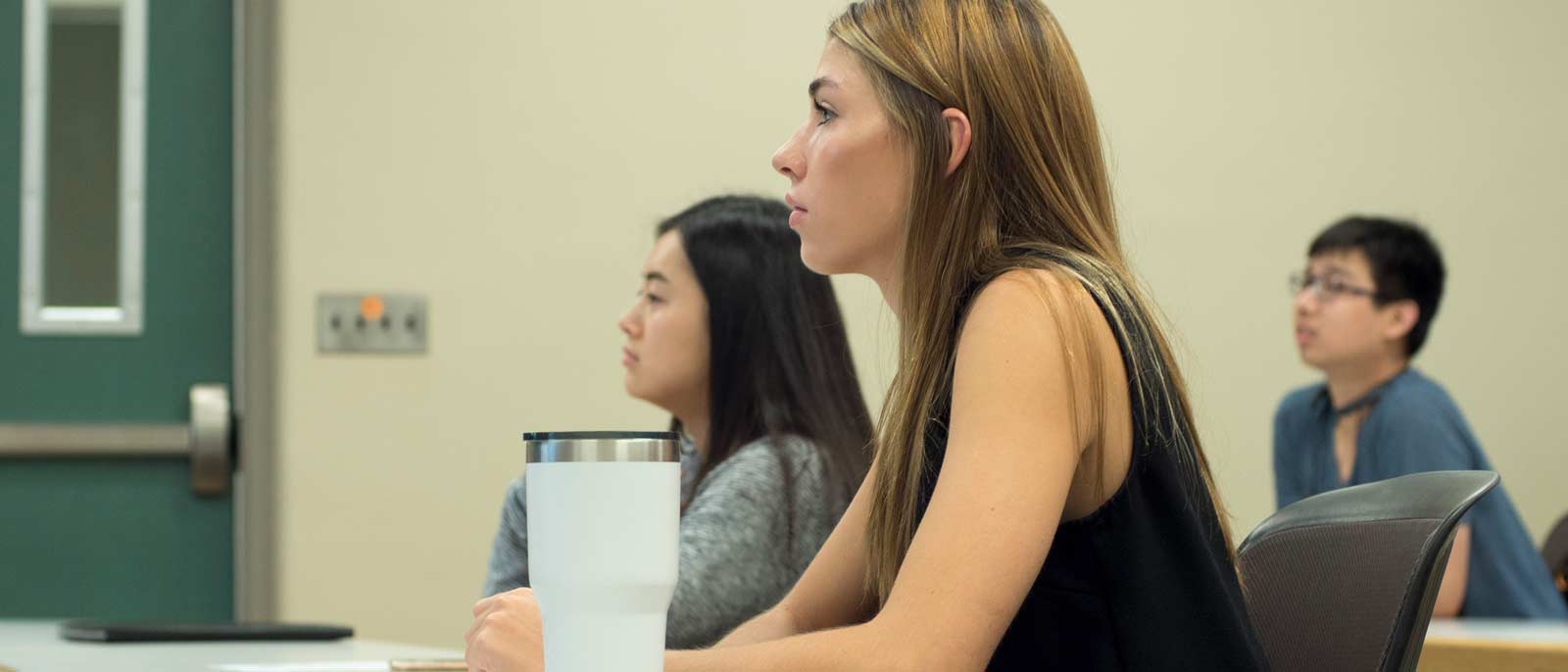 Undergraduate student sits attentively and listens to a presentation.