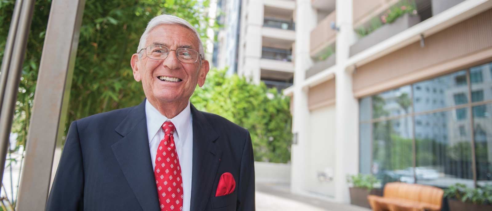 Portrait of business leader and philanthropist Eli Broad, standing outside on a sunny day.