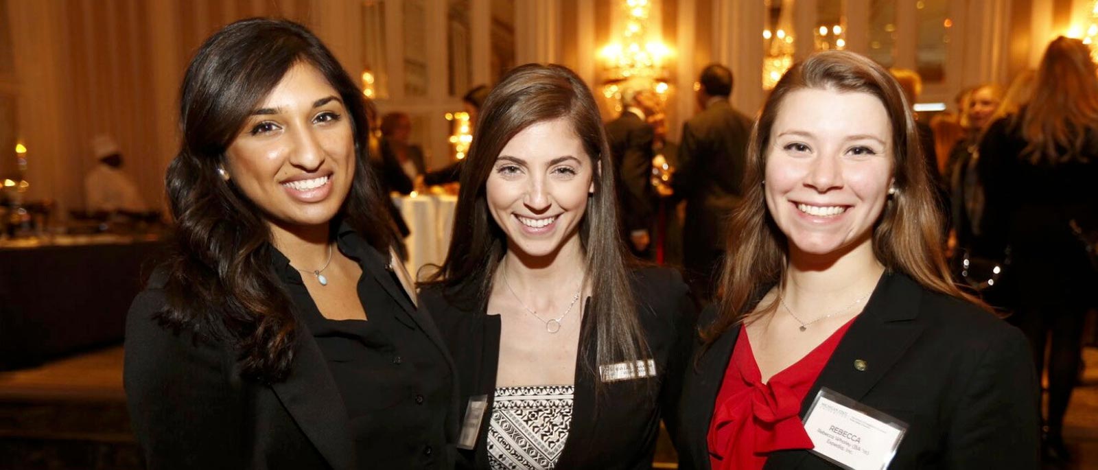 Hospitality Business at MSU students and alumnae pose for a photo at a gathering in a ballroom.