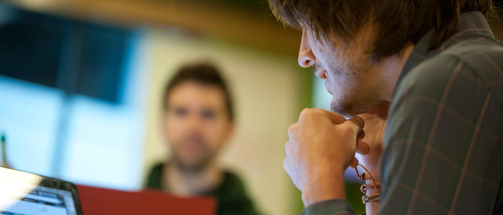 Profile shot of student looking down intently at his laptop screen.