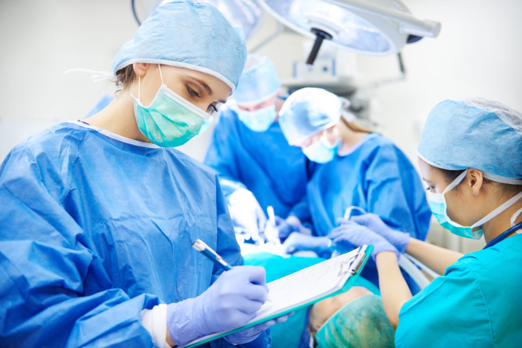 Surgeon writing down notes during an episode of care in an operating room.