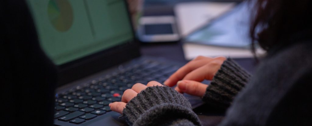 Zoomed in on a woman's hands as she types on a laptop
