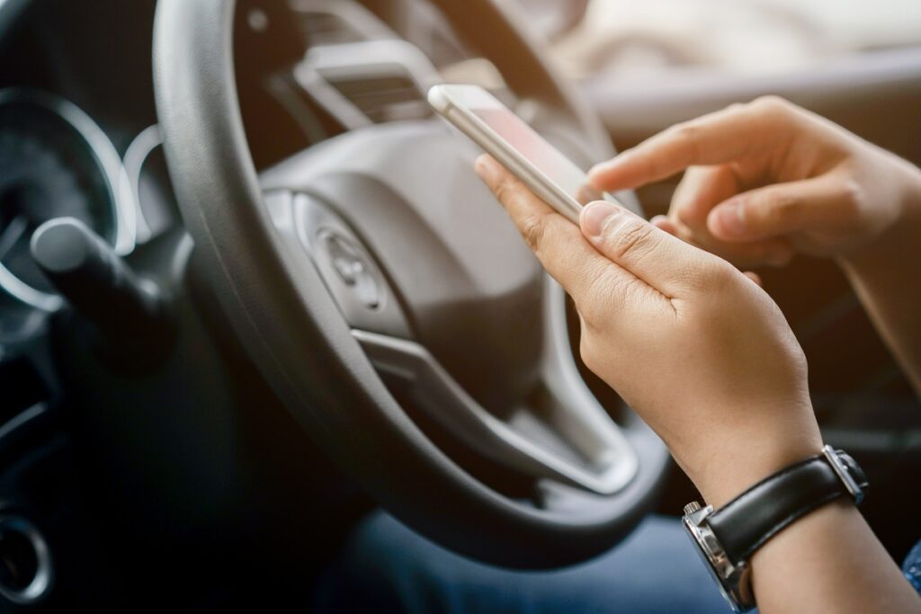 Close up image of woman holding smartphone for using GPS navigation in a car.