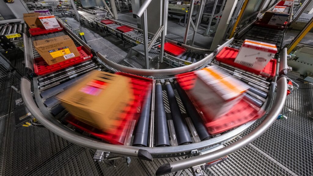 Boxes moving on a conveyer belt, through a supply chain.