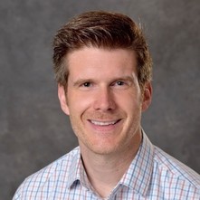 Headshot of a man wearing a plaid shirt