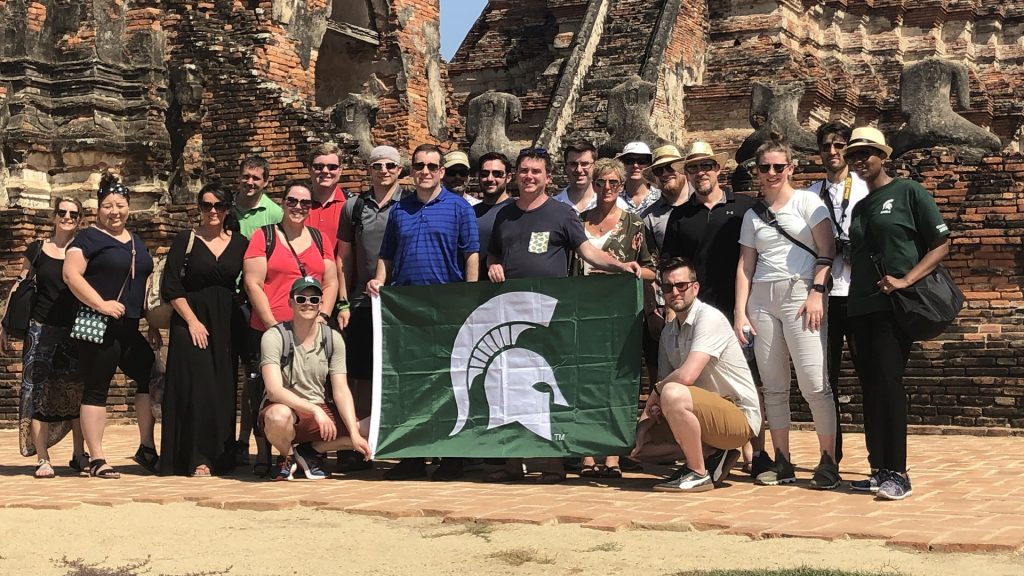 EMBA students hold a Spartan helmet flag in Thailand.