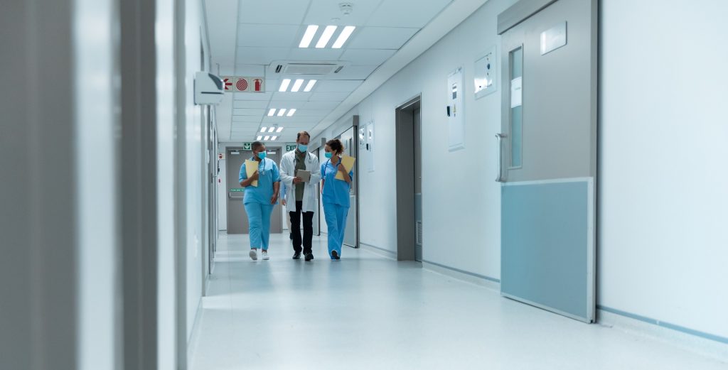 Hospital workers wearing face masks walking down a hallway.