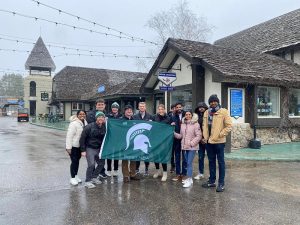 A group of MBA students pose with a Spartan flag outside the Boyne Mountain Resort.