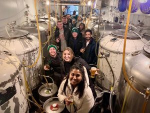A group of MBA students pose inside Short's Brewing Company during a brewery tour.