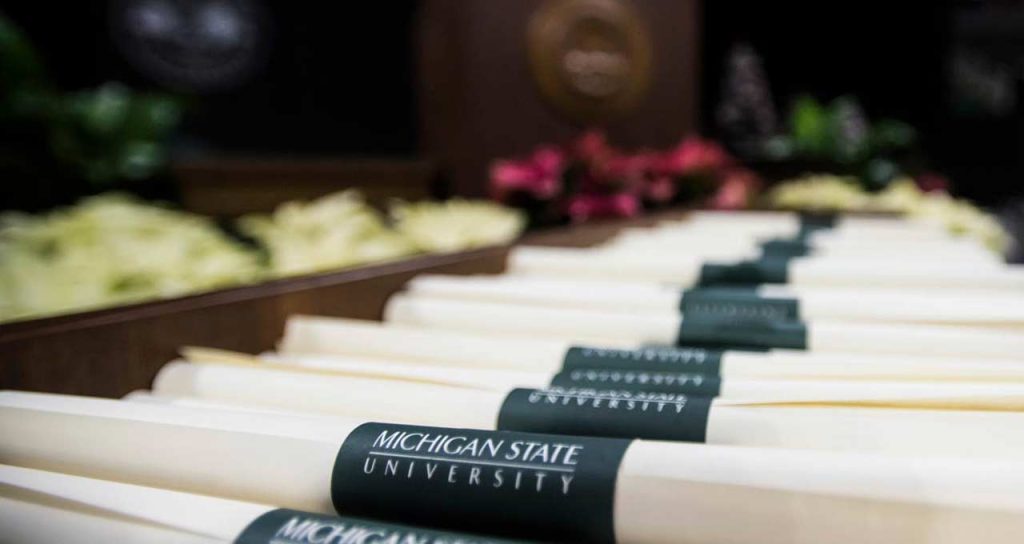 Rolled diplomas stacked together on stage at the MSU Advanced Degree Ceremony in the Breslin Student Events Center.