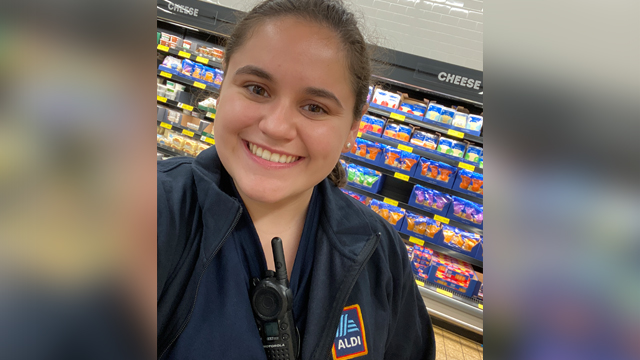 Amy Montalbano wearing an Aldi shirt with walkie talkie in the Aldi Grocery Store