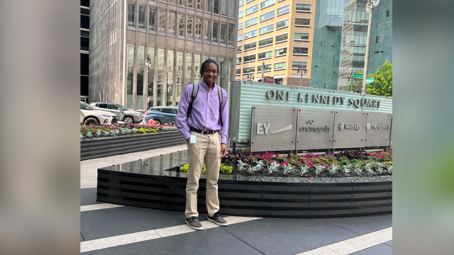 Dakarai Young standing outside the Ernst & Young building sign