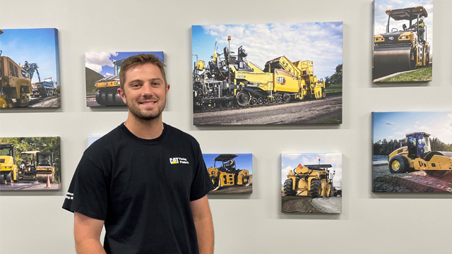 Jacob Levack standing in front of wall with Caterpillar tractor canvases.