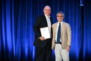 John Hollenbeck on stage receiving an award. (Photo courtesy of AOM)