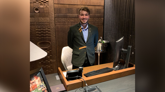 Tyler Dahms standing behind a Hotel concierge desk