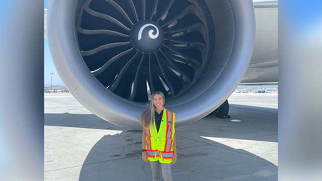 Viktoria Mihailovic standing in front of a United Airlines airplane jet engine wearing a yellow Safety Vest