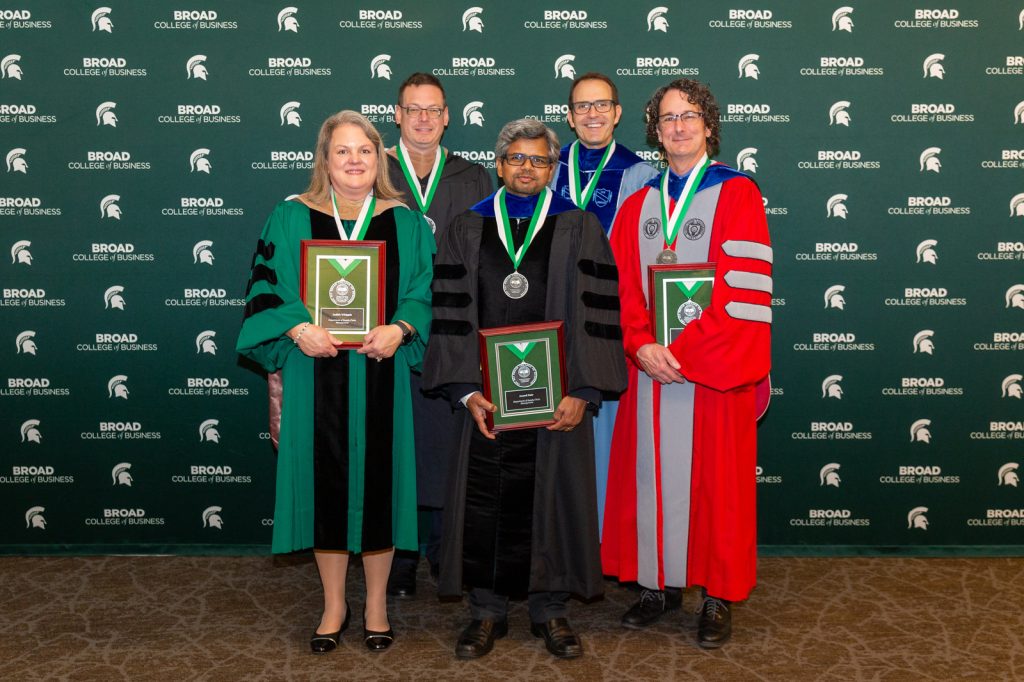 Broad faculty Judith Whipple, Stephen Schiestel, Anand Nair, Kevin Markle and Stanley Griffis wear academic regalia and pose in front of a Broad College banner at the 2022 Faculty Recognition Dinner and Investiture Ceremony.