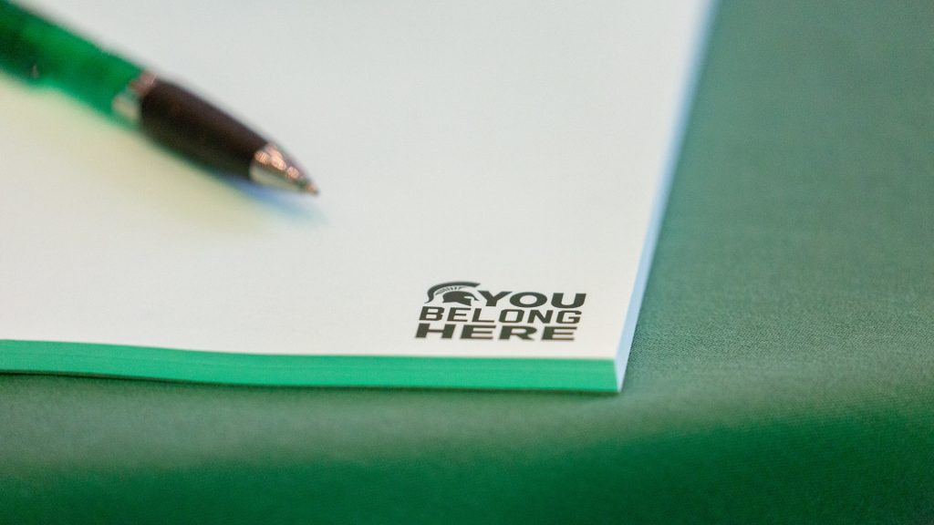 The Broad College has shown a commitment to building an inclusive environment through recent initiatives like a school climate survey. Image shows close up of pen and notepad with Spartan helmet logo and text that reads: You belong here.