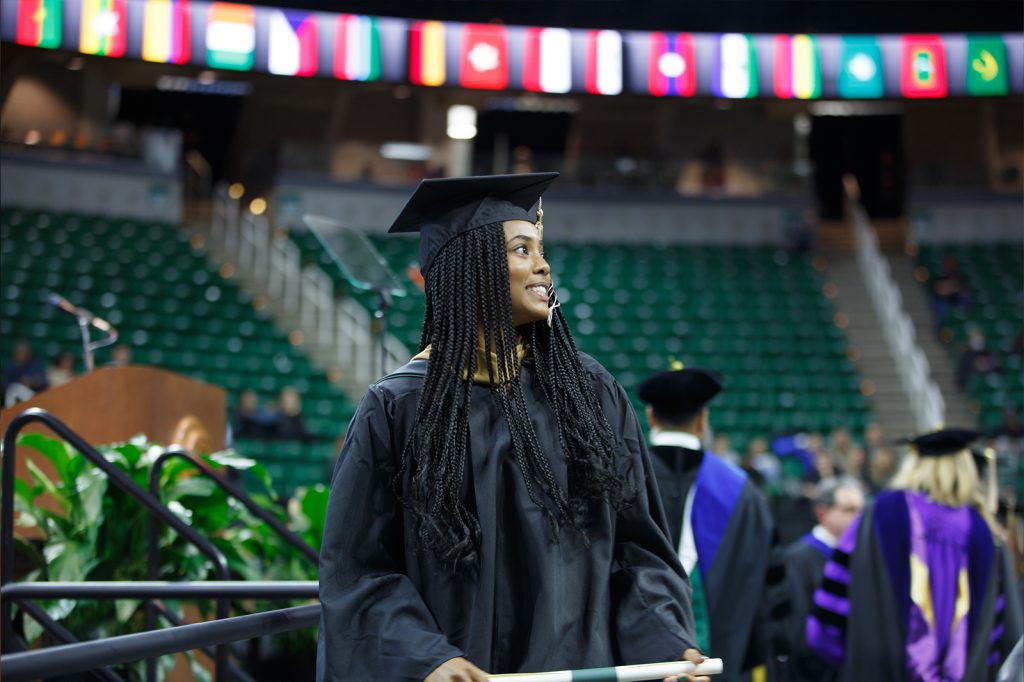 A Broad master's graduate looks up at the crowd as they cross the stage at commencement.