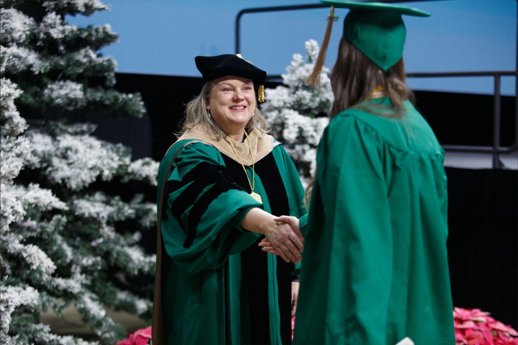 Broad College Interim Dean Judith Whipple shakes hands with an undergraduate student as they cross the stage for commencement.