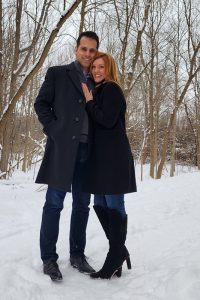 Al Makke and Jenny Abro pose together outside in a wintry, wooded area.