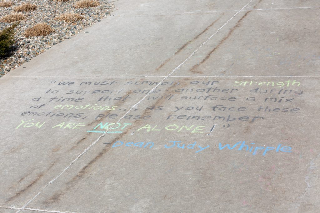 A chalk message on campus sidewalk reads, 