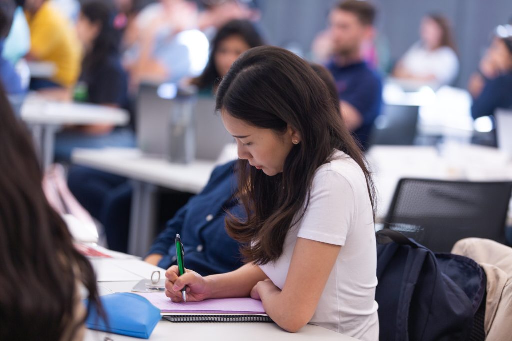 Woman MBA student taking notes in class.