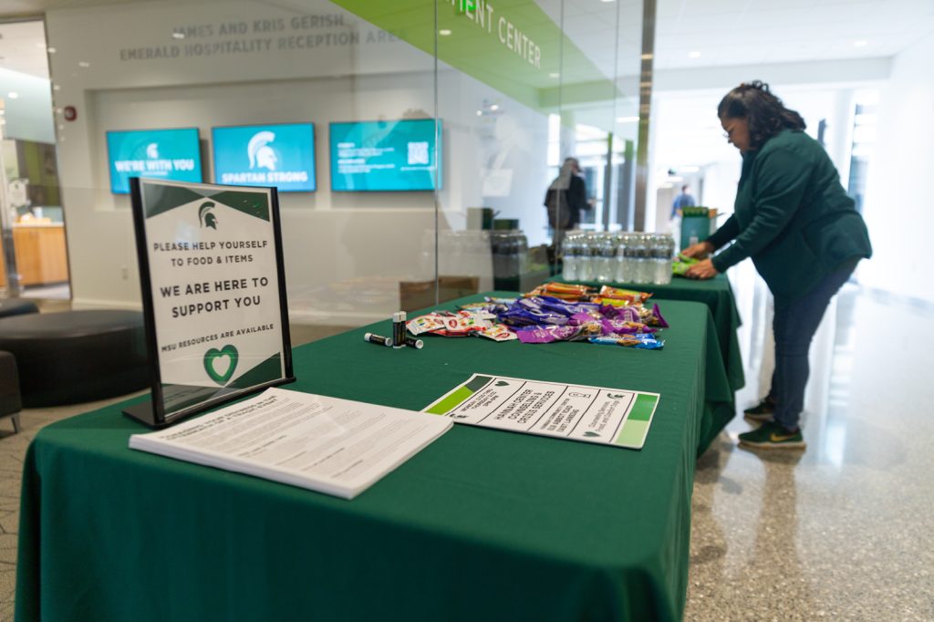 A Broad College staff member sets up a table with resources, snacks and information for students.