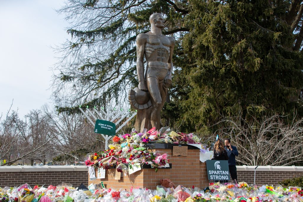 The Spartan statue on MSU's campus, surrounded by flowers, signs and messages of support for the community and students.