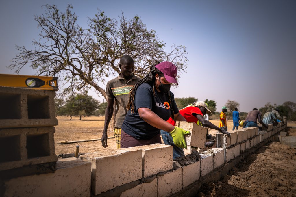 buildOn volunteers construct the walls of a school with cement and cinderblocks.