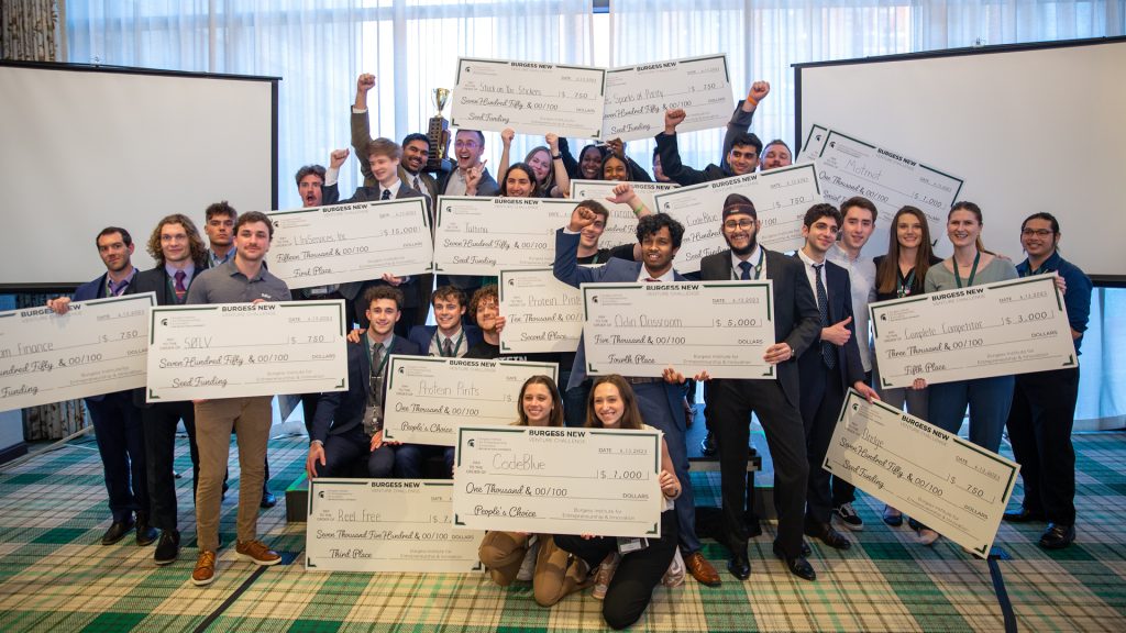 Student winners and finalists at the 2023 Burgess New Venture Challenge holding oversize checks at The Graduate hotel in East Lansing.