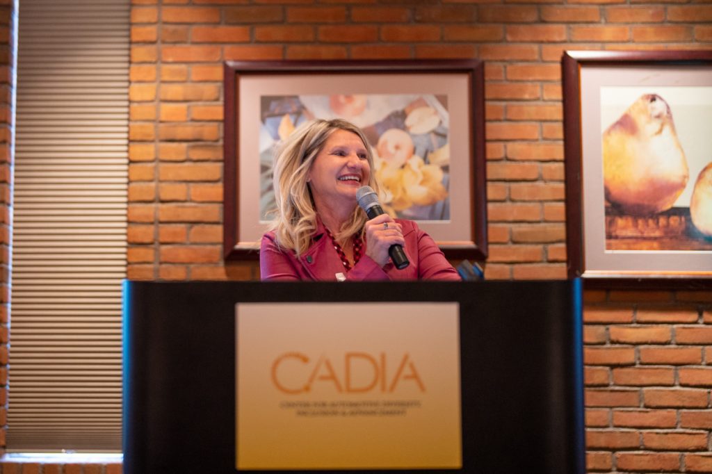 Cheryl Thompson speaking at a podium for a CADIA event.