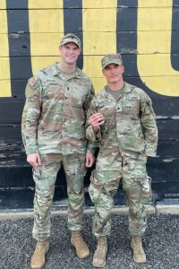 Sean Gordon poses with another MSU ROTC cadet in front of a painted brick mural.