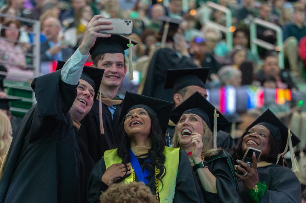 Broad master's graduates stand in the Breslin Center bleachers to take a selfie.