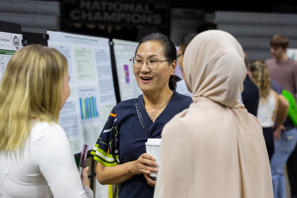 Faculty and students talk beside research posters at the 2023 UURAF.