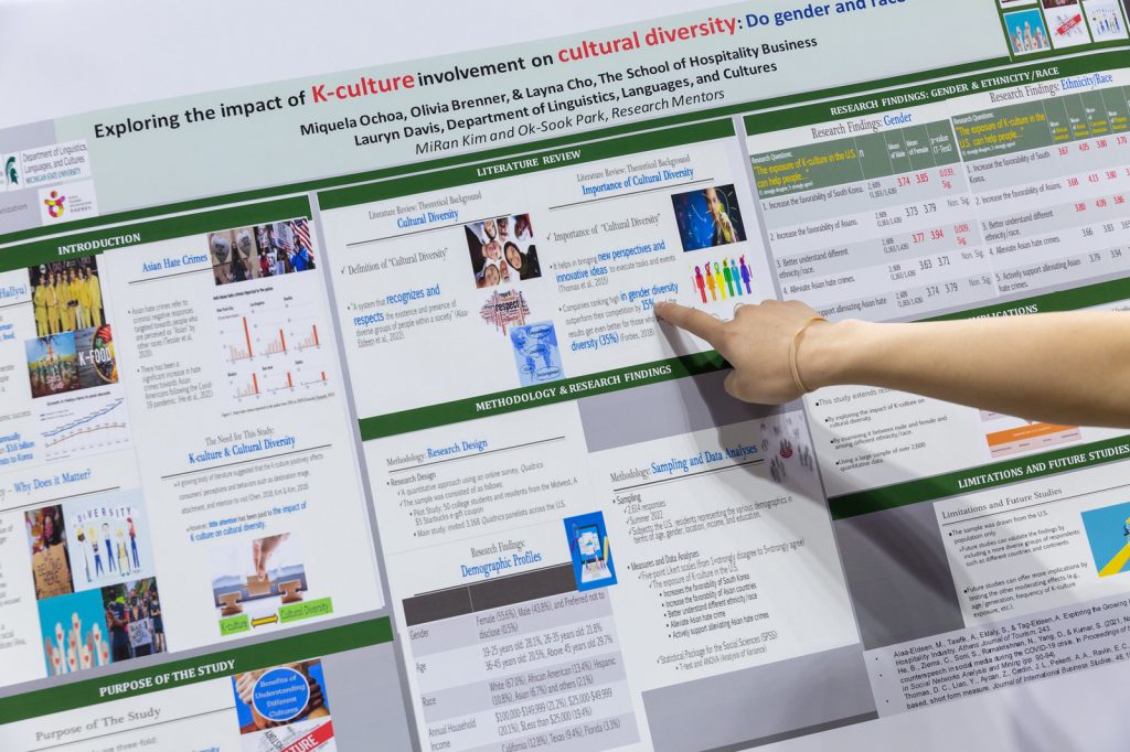Research poster with an anonymous hand pointing to text on the poster.