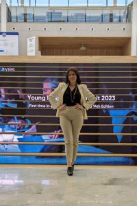 Olivia Cannella poses in front of a staircase with branded graphics for the Young Hospitality Summit.