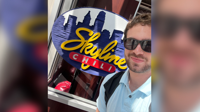 Caden Opsommer taking a selfie in front of a Skyline Chili sign