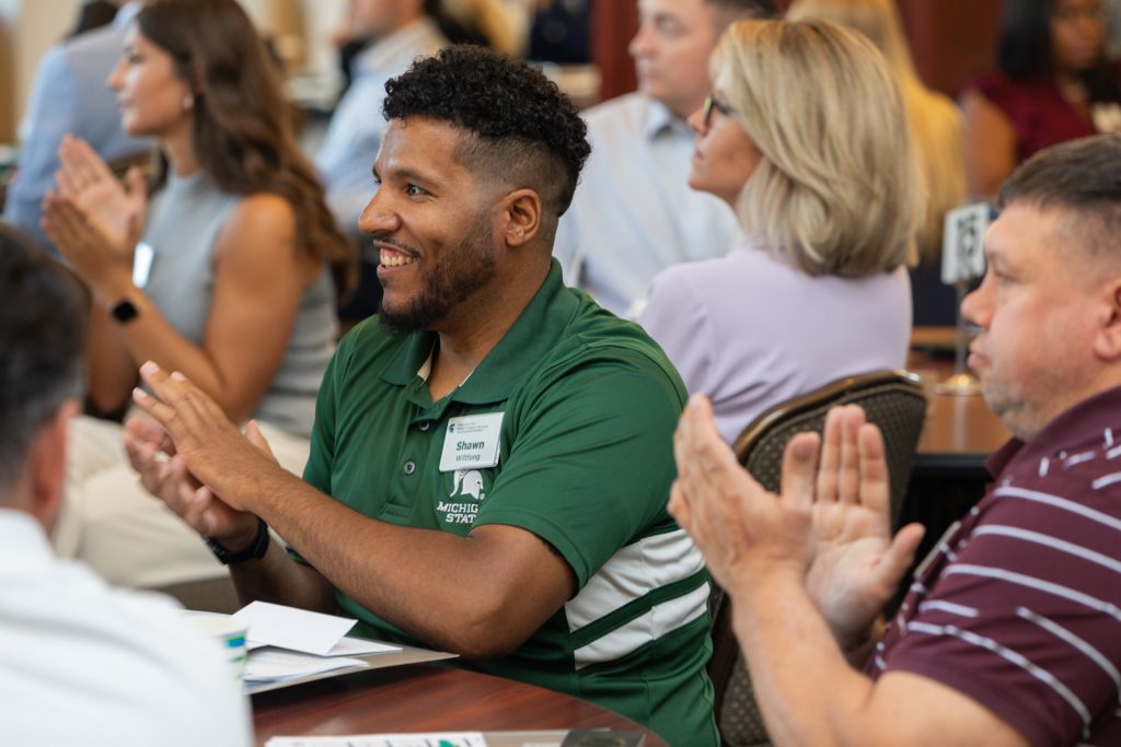 Executive MBA students applaud during orientation.