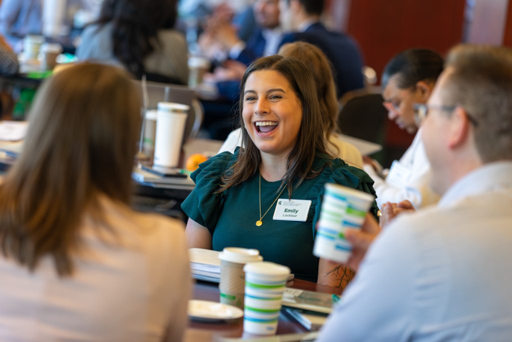 A woman smiles while interacting with her new teammates during the Executive MBA orientation.