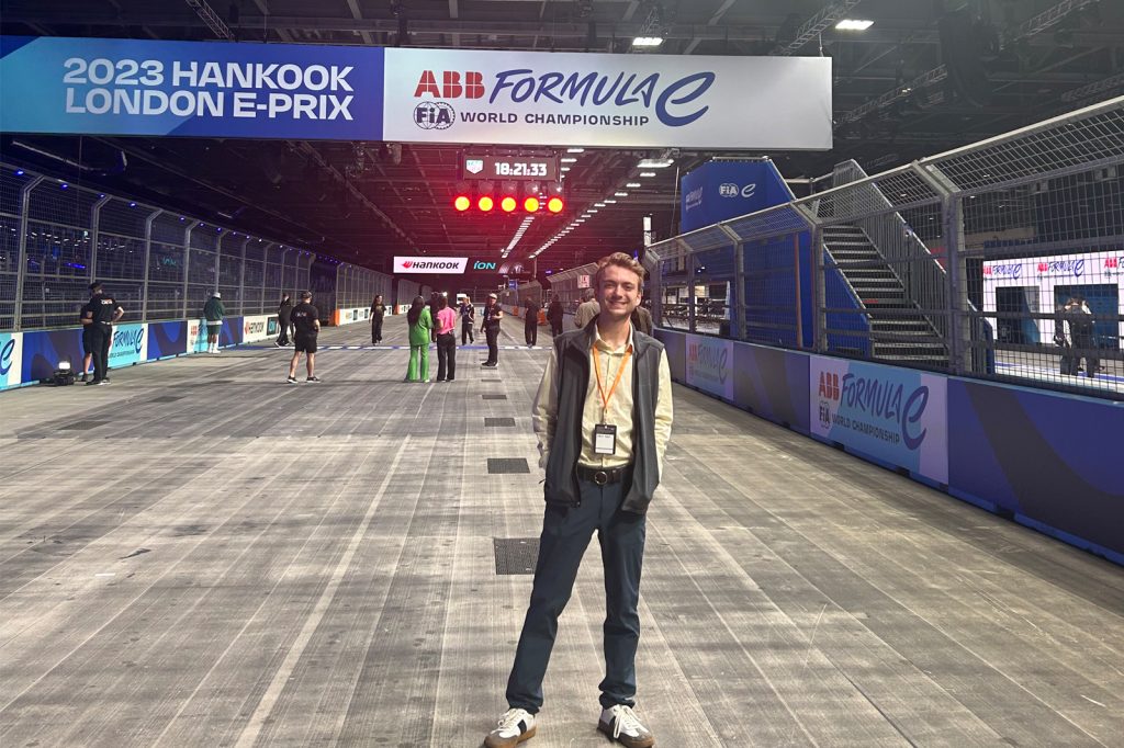 Jack Falk stands under a banner that says 2023 Hankook London E-prix, ABB Formula E World Championship during his internship experience.