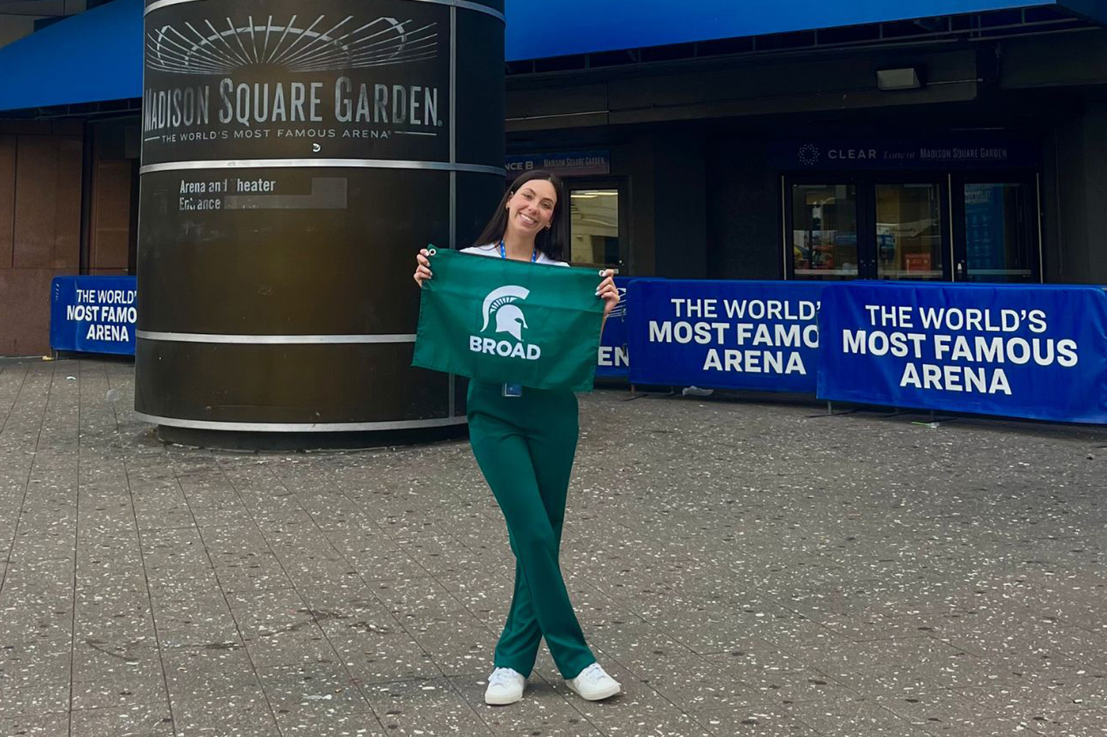 Maddison Rizzo holds a Broad flag outside the main entrance of Madison Square Garden during her 2023 internship experience.