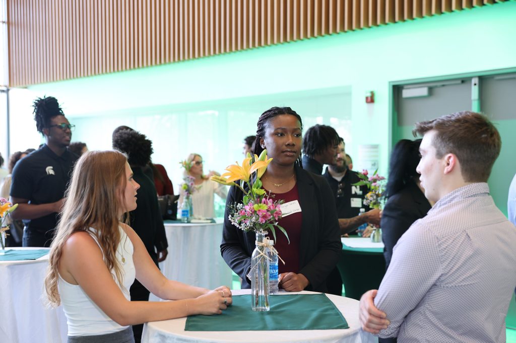 Students gather around a high-top table and talk during the MSU NIL Summit.