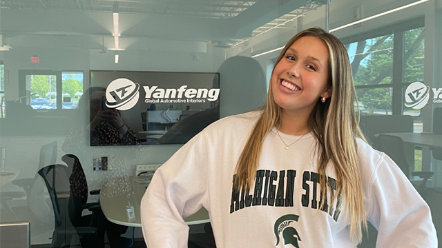 Maddie Ritsema posing in front of the Yanfeng logo