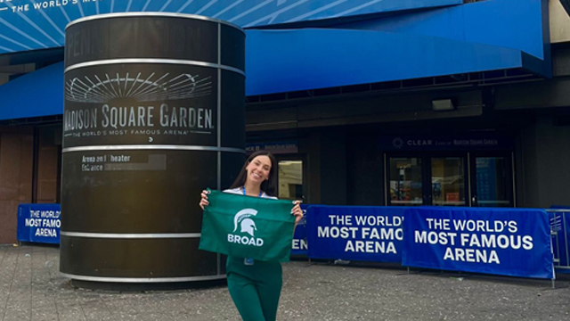 Maddison Rizzo holding a Broad College flag in front of Madison Square Garden