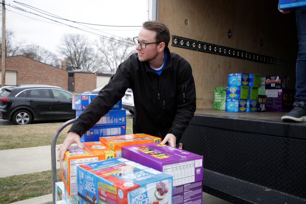 Collin Haggerty unloads bulk boxes of juice and food from a truck as part of his sports business management role with the Pistons.